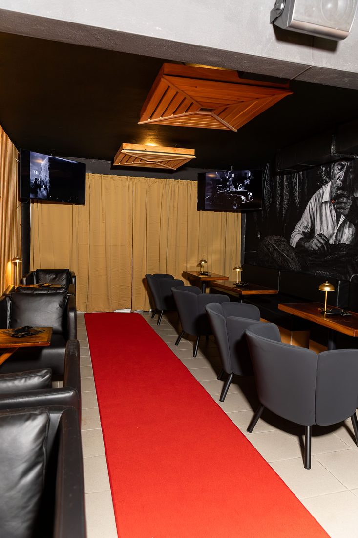 La alfombra roja del speakeasy, con el sofa de cuero y las mesas