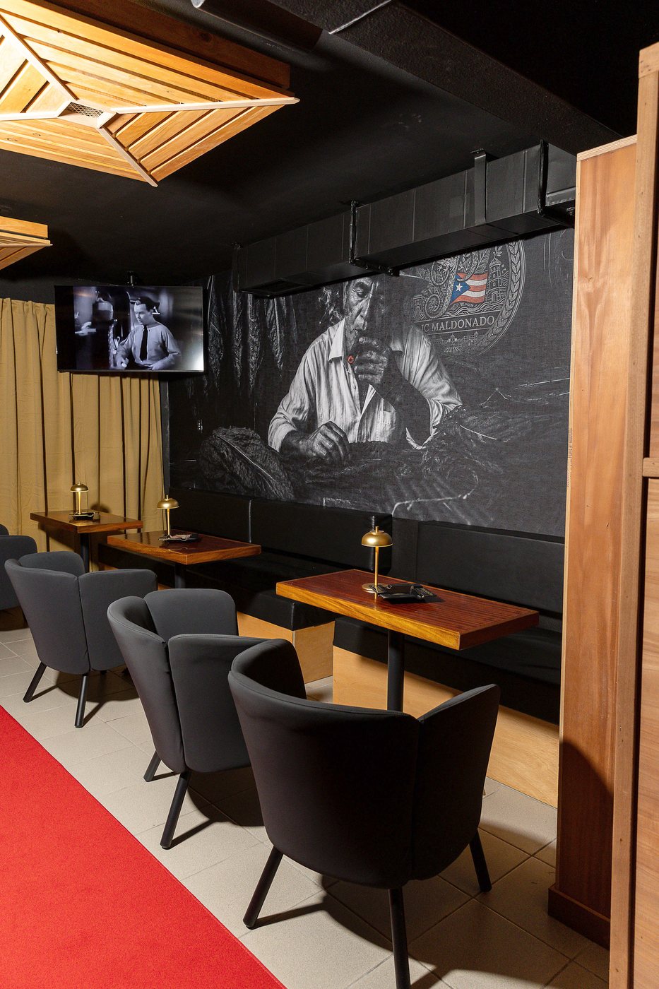 El mural del torcedor de cigarros sobre la pared del speakeasy, con mesas y butacas